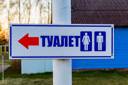Signpost on the street in the form of an arrow and the words "toilet"
