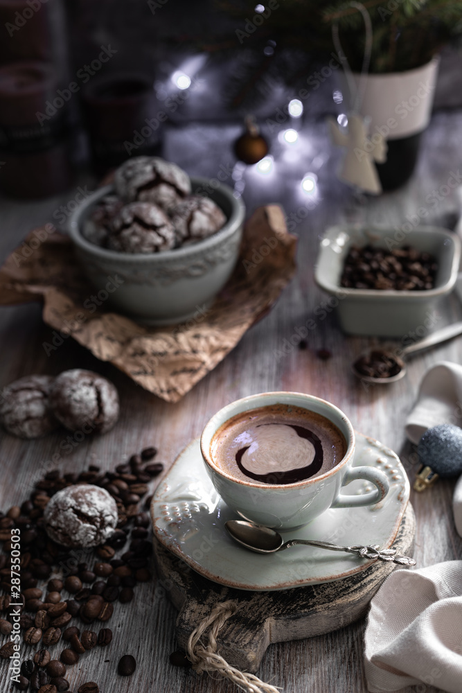 Cup of coffee with coffee beans and chocolate chip cookie with fried New Year lights on a beautiful brown background.
