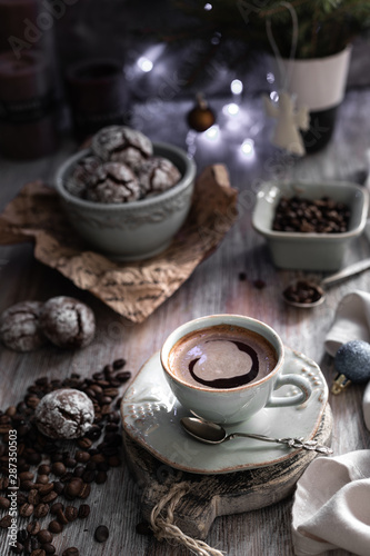 Cup of coffee with coffee beans and chocolate chip cookie with fried New Year lights on a beautiful brown background.