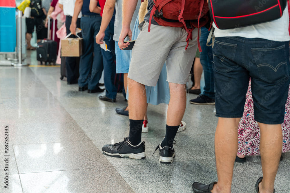 Queue of Asian people waiting at boarding gate at airport. Close-up composition