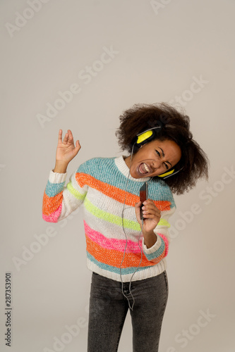 Beautiful young african american woman in headphones listening to music and dancing having fun