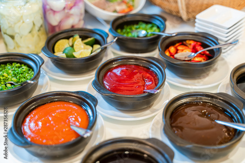 Various bowls of assorted sauces, dips on a asian cuisine buffet