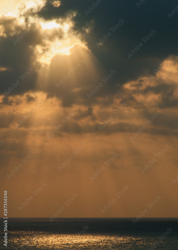 The evening rays of the sun over the Mediterranean Sea. Yellow clouds background The evening rays of the sun over the Mediterranean Sea. Yellow clouds background
