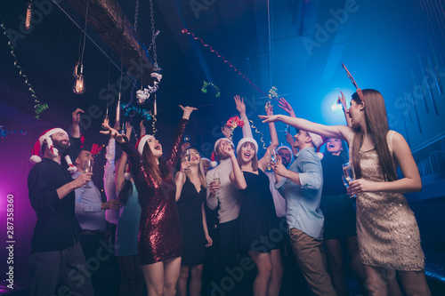 Portrait of nice-looking attractive smart cheerful cheery positive glad ladies and guys having fun dream celebratory flying decorative elements at luxury fogged lights nightclub indoors