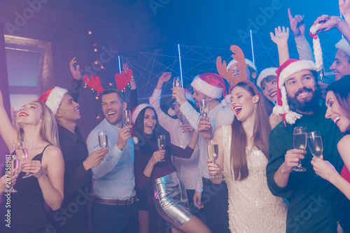 Portrait of nice-looking attractive glamorous smart stylish trendy cheerful cheery positive girls and guys having fun December tradition chill out in luxury place fogged nightclub indoors
