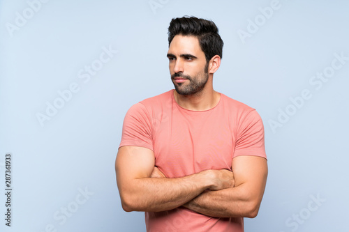 Handsome young man in pink shirt over isolated blue background portrait