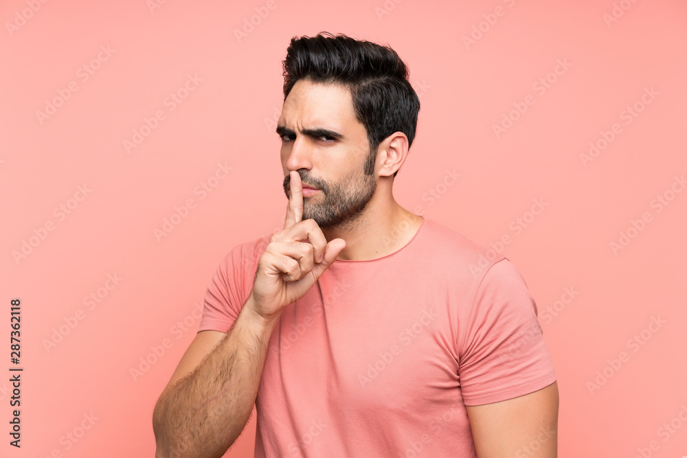 Handsome young man over isolated pink background doing silence gesture