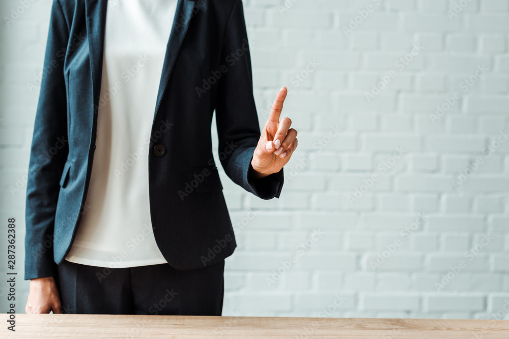 cropped view of businesswoman in formal wear pointing with finger while standing in office cropped view of businesswoman in formal wear pointing with finger while standing in office