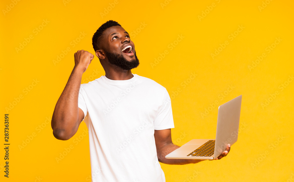 Excited african man celebrating win with laptop Excited african man celebrating win with laptop