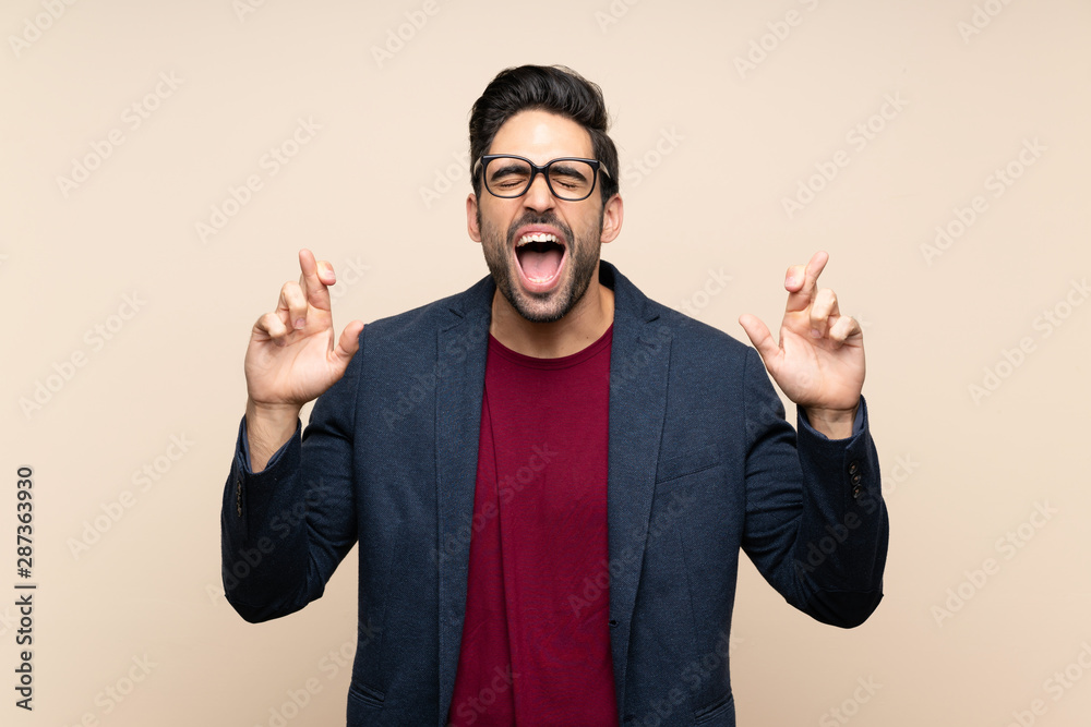 Handsome young man over isolated background with fingers crossing Handsome young man over isolated background with fingers crossing