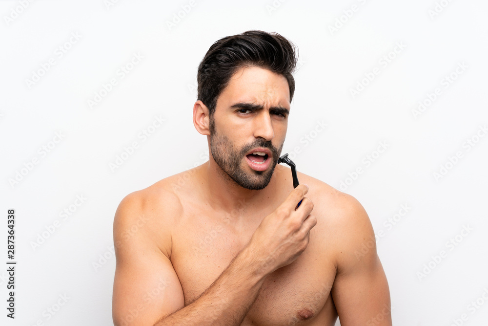 Man shaving his beard over isolated white wall Man shaving his beard over isolated white wall