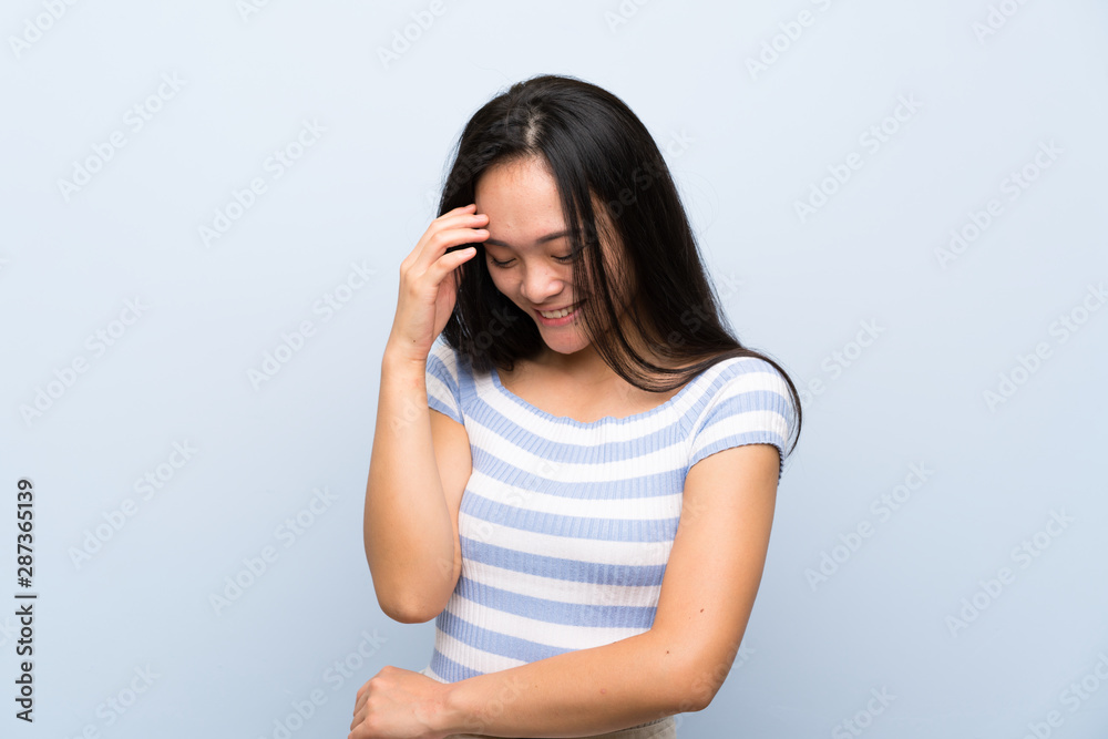 Teenager asian girl over isolated blue background laughing Teenager asian girl over isolated blue background laughing