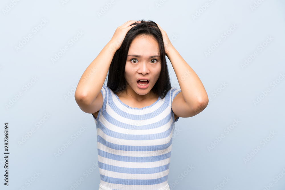 Teenager asian girl over isolated blue background with surprise facial expression Teenager asian girl over isolated blue background with surprise facial expression