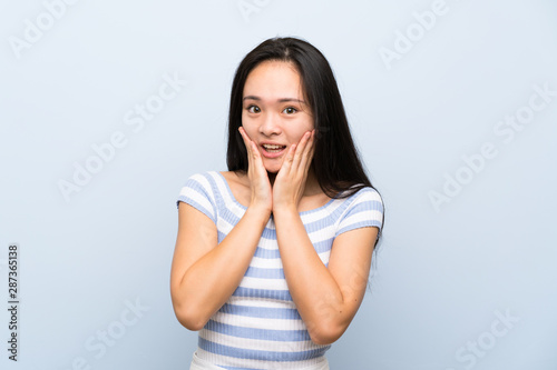 Teenager asian girl over isolated blue background with surprise facial expression