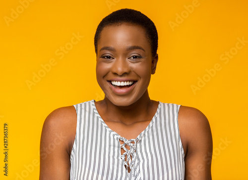 Portrait of laughing african american girl on yellow background © Prostock-studio