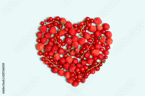 Heart shape assorted berry fruits on blue background.