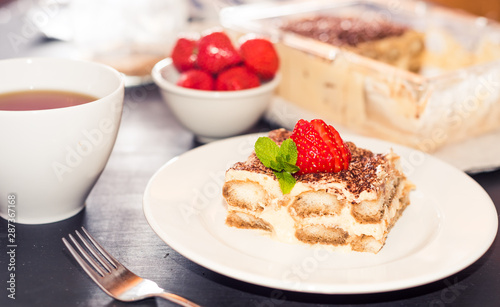 gourmet tiramisu dessert with strawberries in a beautiful plate on a dark background