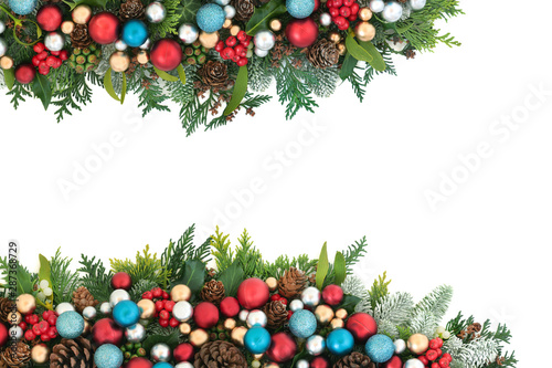 Festive Christmas background border with red, blue and silver ball bauble decorations and winter flora with pine cones on white with copy space.