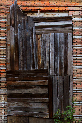 Boarded up windows on a brick wall. Abstract wooden background. Brick wall and wood panels.