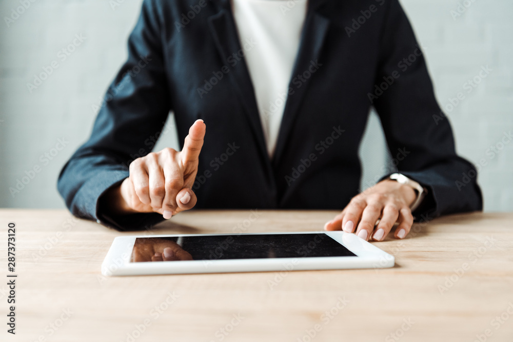 cropped view of woman pointing with finger at digitla tablet with blank screen on table cropped view of woman pointing with finger at digitla tablet with blank screen on table