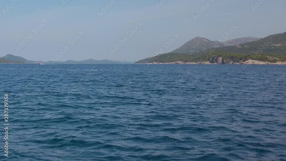A nice panning shot as the boat cuts through the blue waters of the Adriatic, along the rocky coastline. Wide steady zoom shot A nice panning shot as the boat cuts through the blue waters of the Adriatic, along the rocky coastline. Wide steady zoom shot