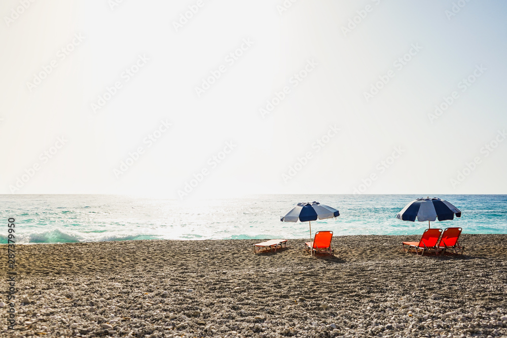 deserted beach with umbrellas and sunbeds at sunset, Lefkada, Greece deserted beach with umbrellas and sunbeds at sunset, Lefkada, Greece
