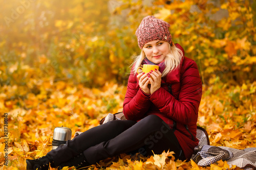 Autumn woman drinking coffee. Fall concept of young woman enjoying hot drink from disposable coffee cup in fall landscape.