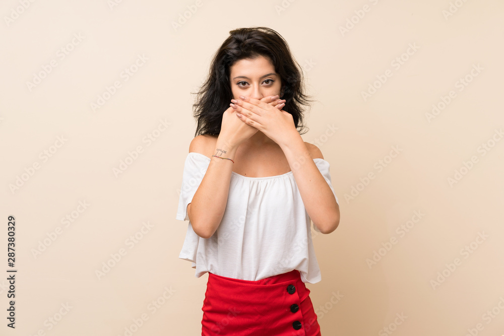 Young woman over isolated background covering mouth with hands Young woman over isolated background covering mouth with hands