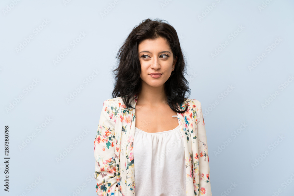 Fototapeta premium Young woman over isolated blue background standing and looking to the side