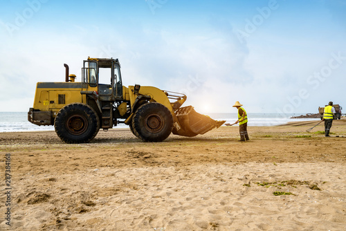 Bulldozers clean up trash on the beach