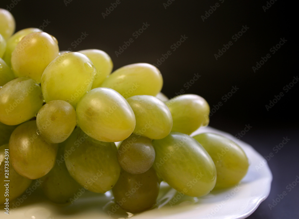 Bunch of green grape isolated on a plate on a black background Bunch of green grape isolated on a plate on a black background