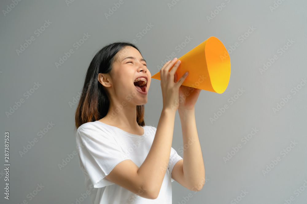 Attractive young Asian woman holding paper megaphone and yelling into. Attractive young Asian woman holding paper megaphone and yelling into.