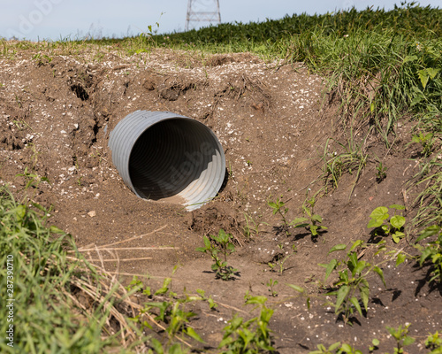 New corrugated metal drainage culvert pipe installed in ditch along road for access to farm field