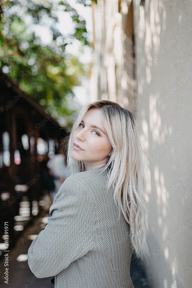 street portrait of a beautiful young blonde woman in a gray jacket and blouse. modern girl.