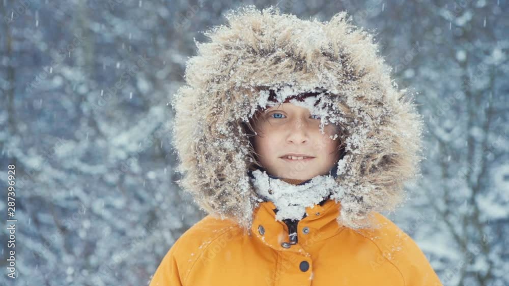Little smiling boy wearing yellow winter jacket with fluffy collar looking into camera Little smiling boy wearing yellow winter jacket with fluffy collar looking into camera
