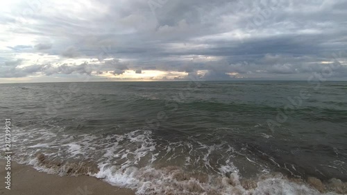 Left pan view Atlantic ocean water waves hitting fine sand shore on dramatic sunrise, Miami Beach photo