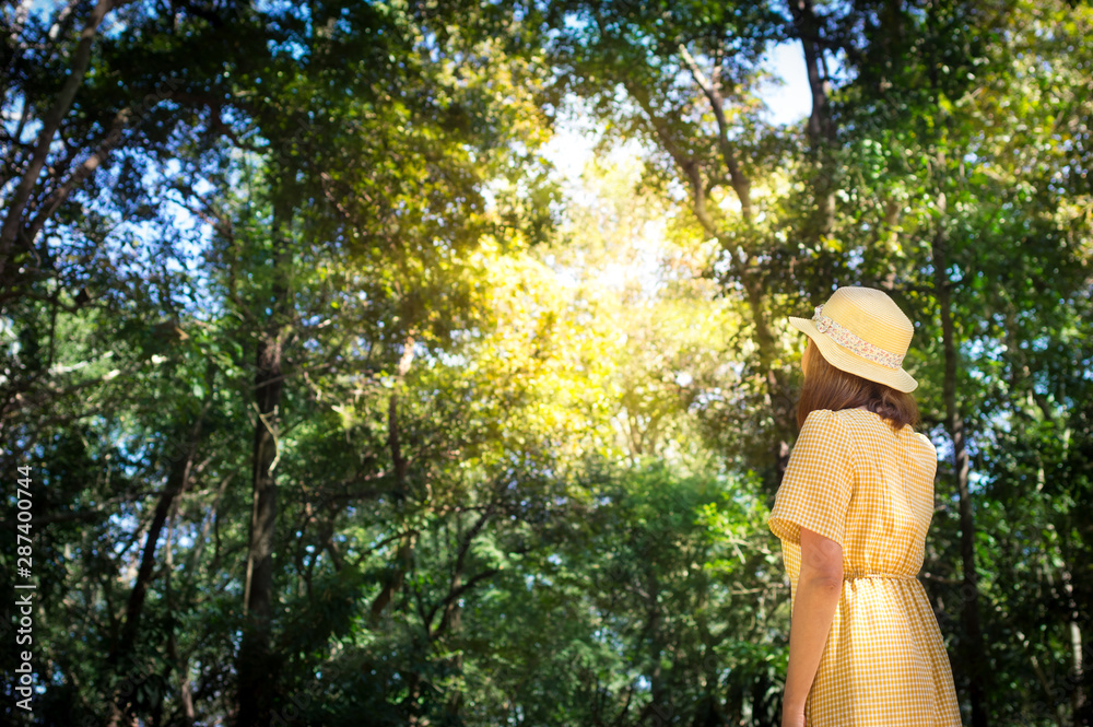 Female in yellow dress standing in forest.
