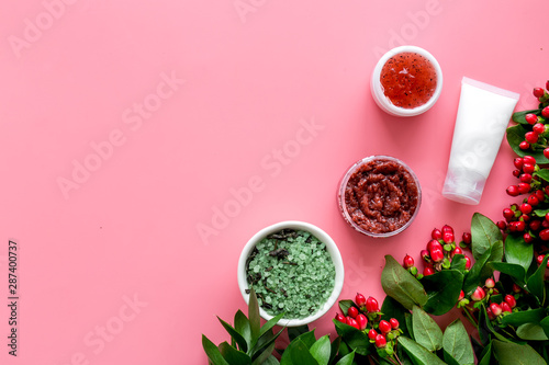 Cosmetics for face with cream, scrub, salt from herbs and berries on pink background top view copyspace photo