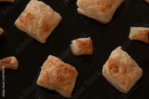 puffs of dough sprinkled with sugar on a baking sheet