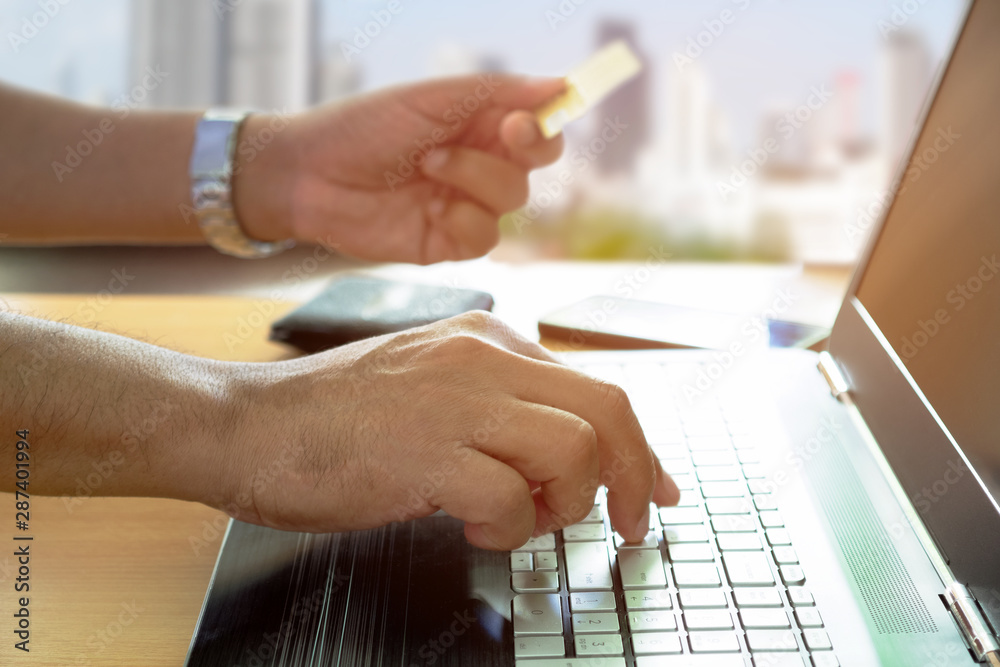 Young man holding credit card shopping online with using laptop at home. Indoor.