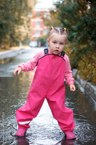 Playful child outdoor jump into puddle in boot after rain on wak, seasonal fun game © misskaterina