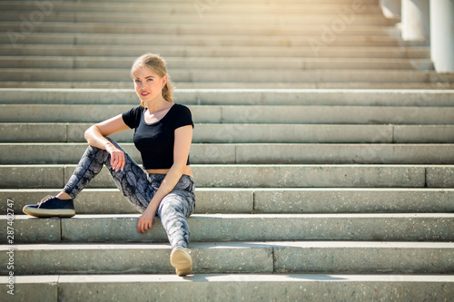 beautiful young woman in sportswear resting on the steps after jogging