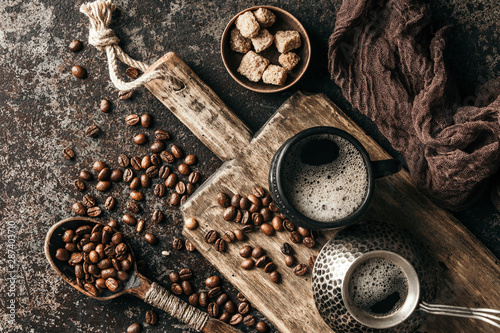 Coffee on wooden board with coffee beans on dark textured background. Top view with copy space. Background with free text space. © zadorozhna