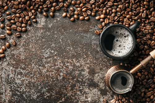 Coffee cup and coffee beans on dark stone background. Top view with copy space. Background with free text space.