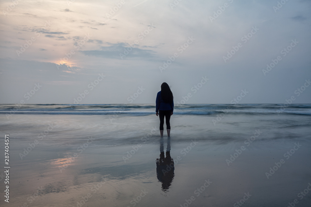 Naklejka premium Attraktive Frau steht allein am Strand