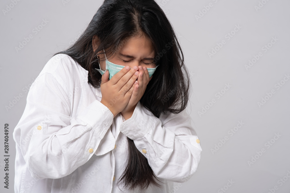 Flu cold or allergy symptom. Sick young asian woman sneezing in mask isolate on grey background. Health care. Studio shot. Business woman wears a mask and coughing, Free from copy space. Flu cold or allergy symptom. Sick young asian woman sneezing in mask isolate on grey background. Health care. Studio shot. Business woman wears a mask and coughing, Free from copy space.