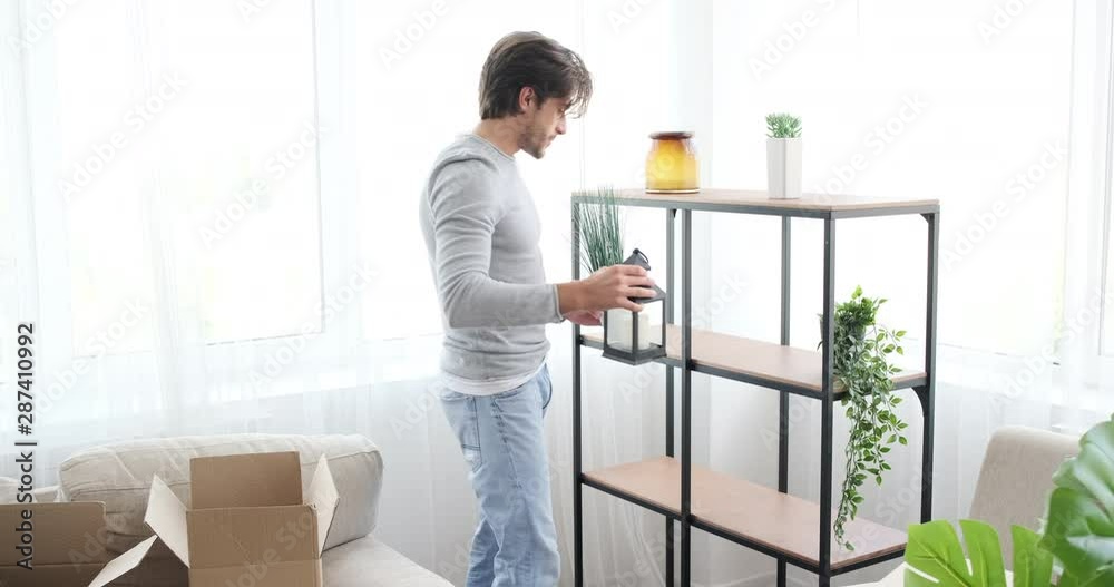 Man having fun while unpacking boxes and decorating his new house Man having fun while unpacking boxes and decorating his new house