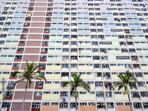 Dense colourful flat houses wtih palm trees respresenting the over population of Hong Kong and instense dense housing photo