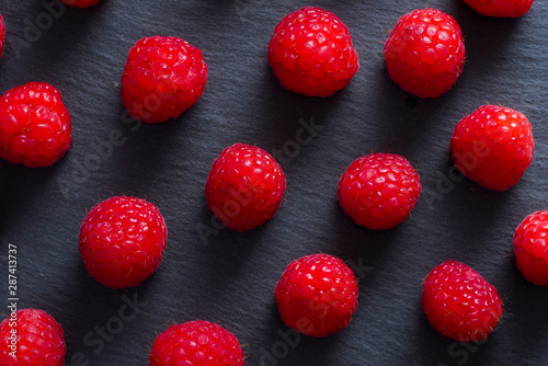 Closeup view from above of red raspberries over a blackboard plate.