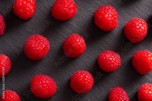 Closeup View from above of red raspberries over a blackboard plate.